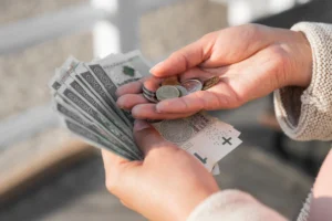 La imagen muestra de forma destacada la mano de una mujer sosteniendo billetes y monedas. Ilustra el texto sobre cuenta bancaria para extranjeros.