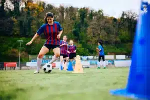 La imagen muestra a un equipo de fútbol femenino entrenando en el campo e ilustra el texto sobre la visa para deportistas.