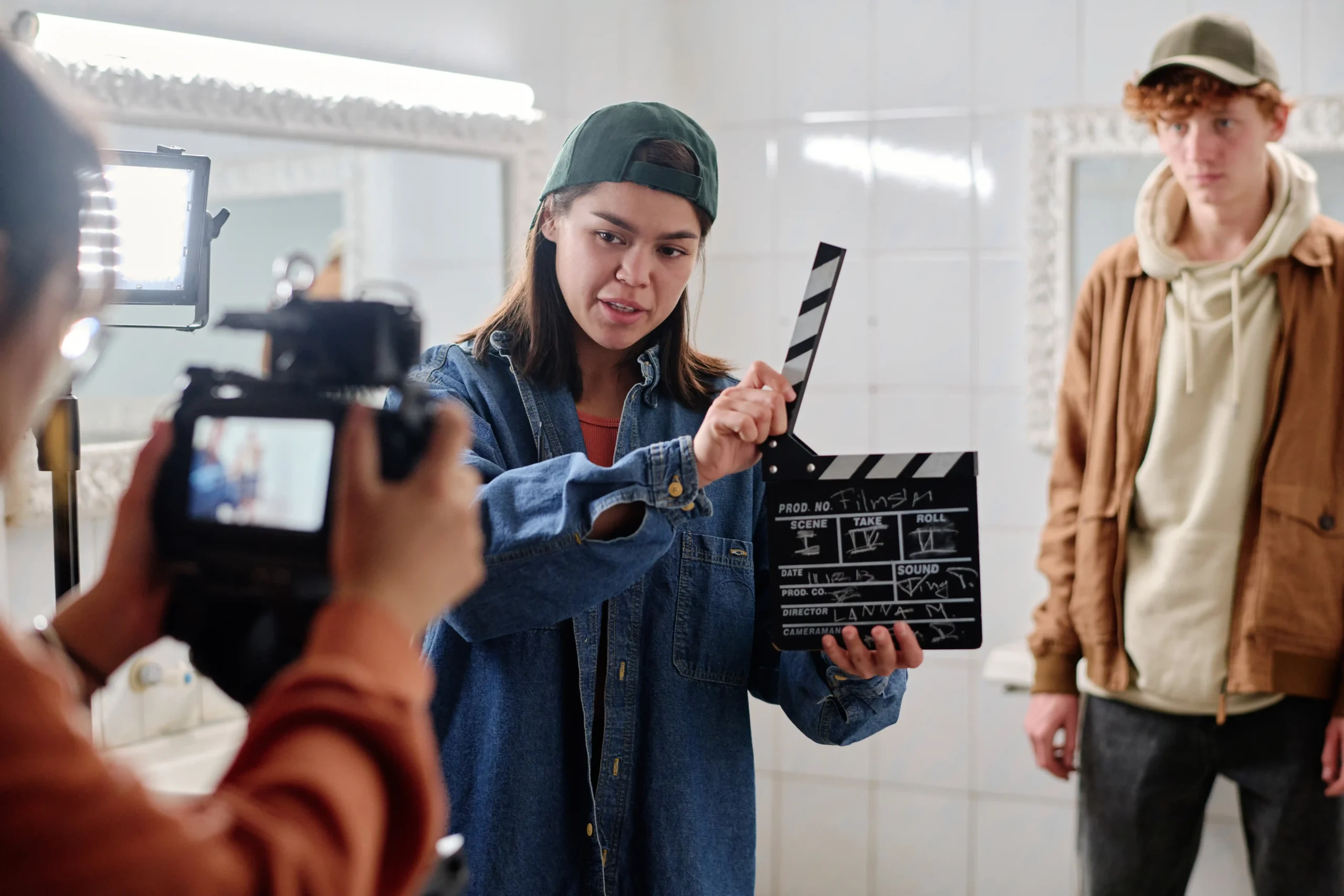 The image shows a filmmaker holding a clapperboard, standing in front of a camera, filming. It illustrates the text on Foreign Filming in Brazil.