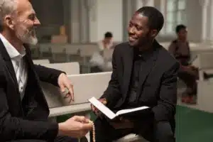 The image shows a young pastor advising an older man in a church. It illustrates the text about the visa for religious activities.