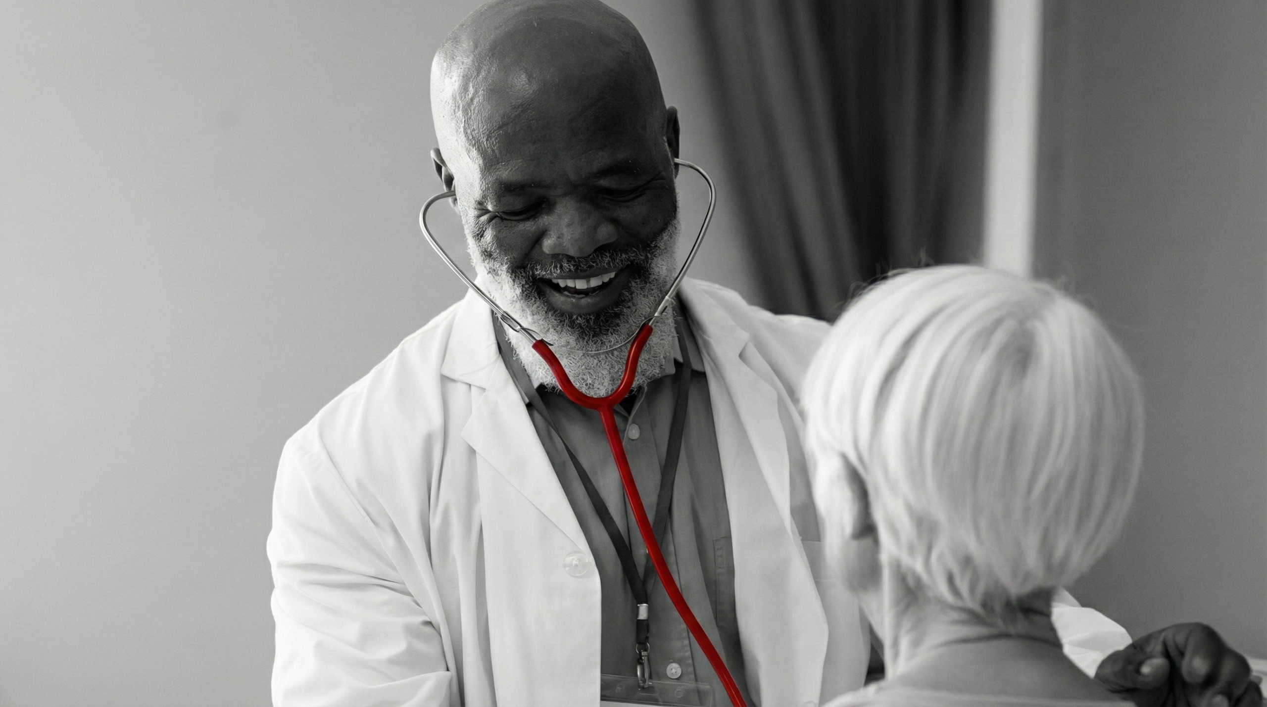 A imagem mostra um médico, auscultando o coração de uma paciente, enquanto sorri.