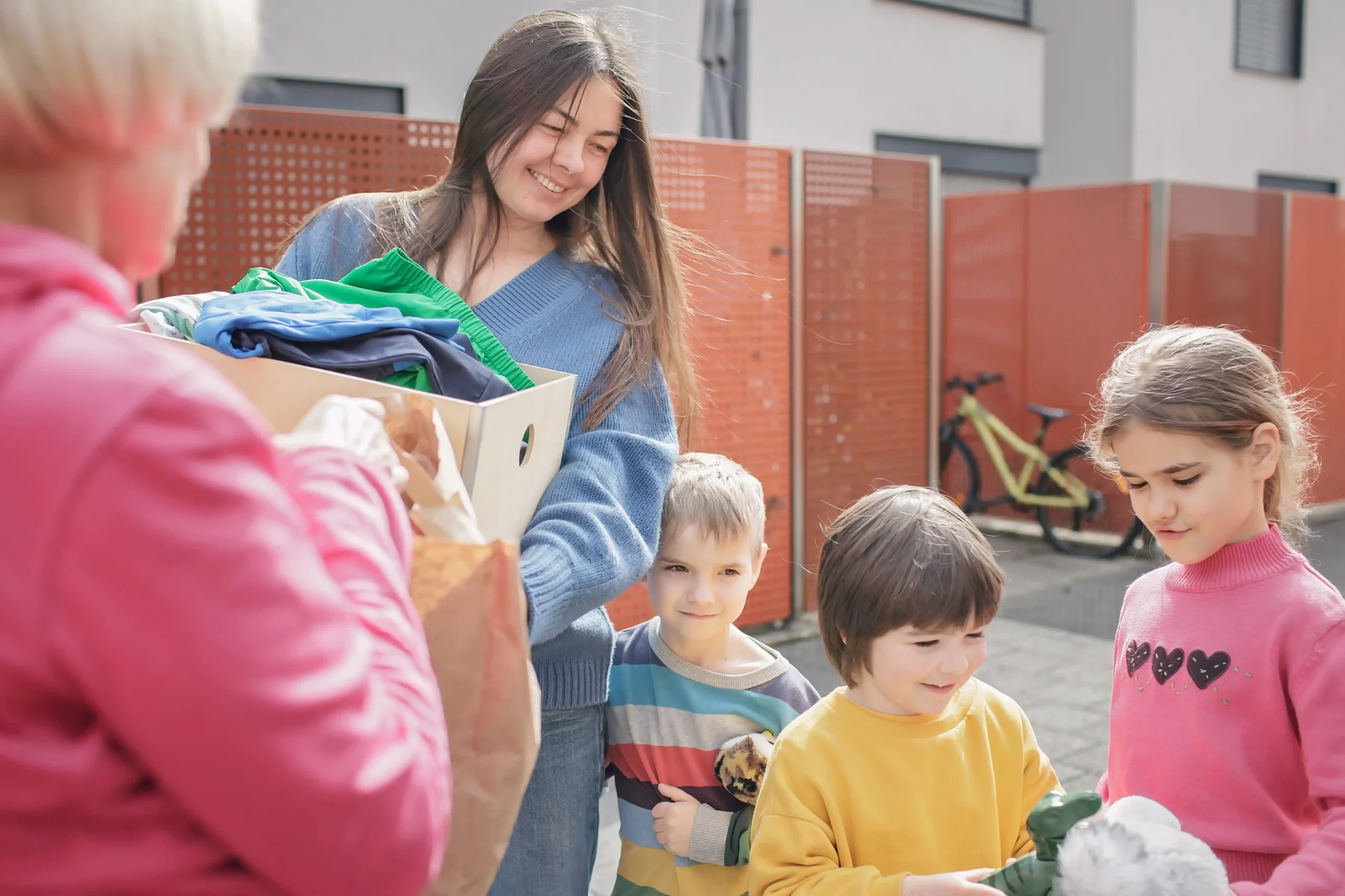 The image shows a woman giving clothes and toys to children, in a volunteer job. Illustrates a text about Volunteer visa in Brazil.