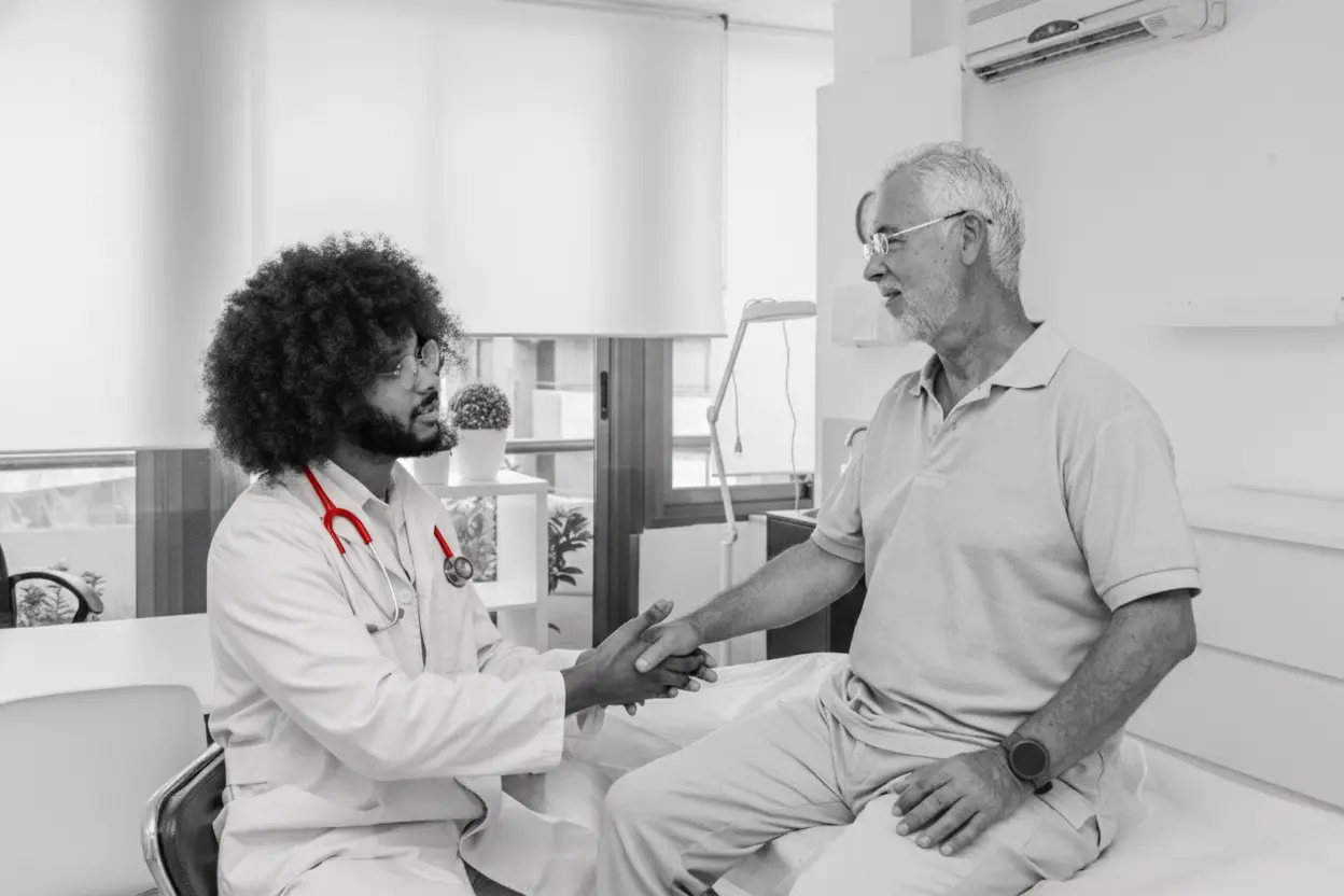 A imagem mostra um médico, em seu consultório, atendendo um paciente.