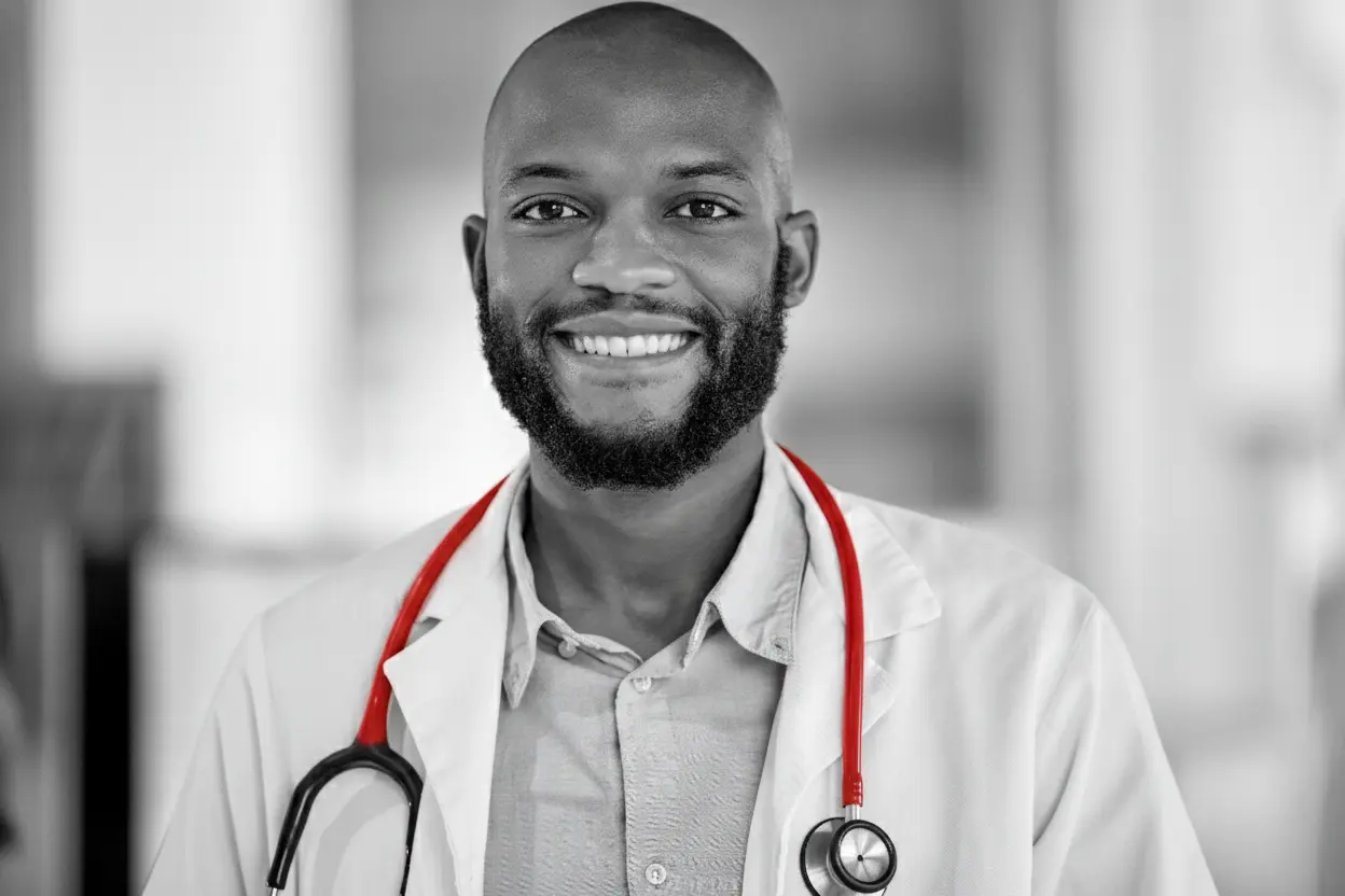 A imagem mostra um médico, de jaleco e estetoscópio em volta do pescoço, sorrindo para a câmera.