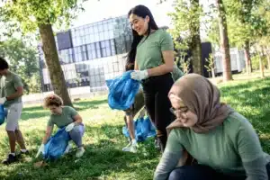 La imagen muestra a un grupo de voluntarios en un parque recogiendo basura. Ilustra el texto sobre la Visa de voluntariado en Brasil.