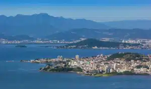 La imagen muestra una vista aérea de la ciudad de Florianópolis, Brasil. Ilustra el texto sobre Florianópolis.