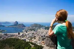 Image one shows a woman with her back turned, looking at the landscape of Rio de Janeiro and Pão de Açúcar. It illustrates the text about Foreigners in Brazil.